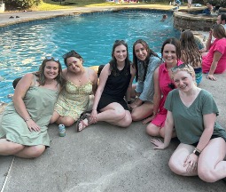 six residents sitting by a swimming pool